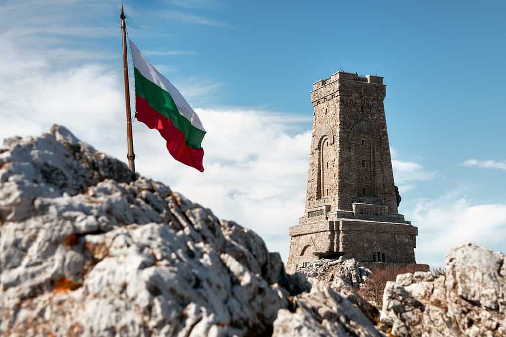 Waving flag of Bulgaria and Shipka memorial monument of Bulgarian liberty