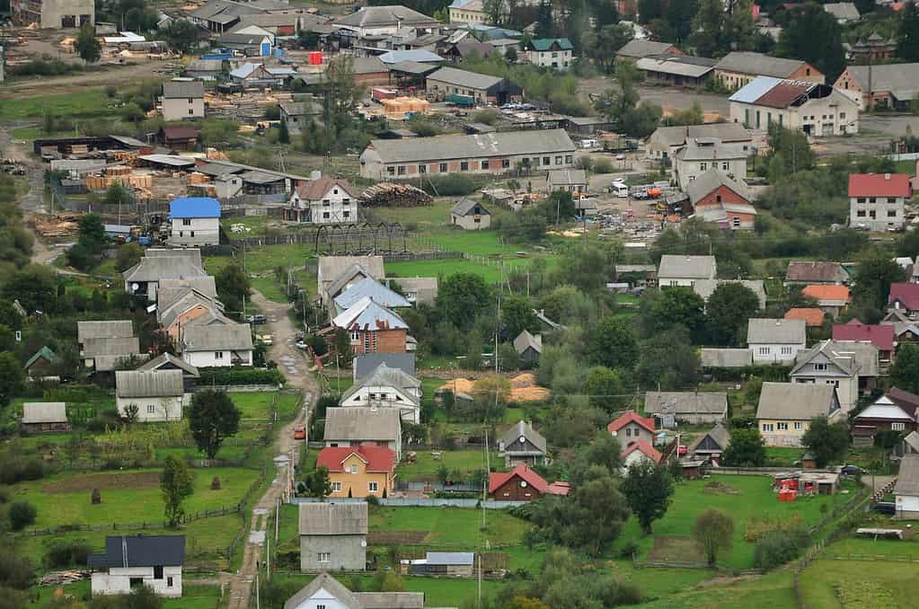 A beautiful view of the village of Mezhgorye, Carpathian region. A lot of residential buildings surrounded by high forest mountains and long river