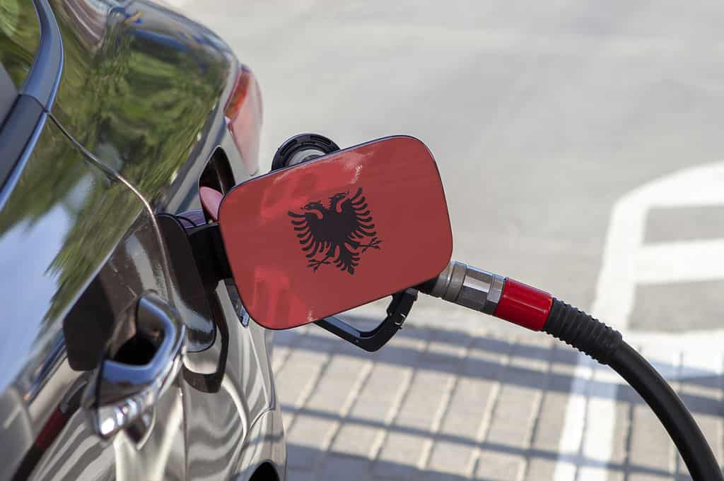 Flag of Albania on the car's fuel tank filler flap. Fueling car with petrol pump at a gas station. Petrol station. Gasoline and oil products. Close up.
