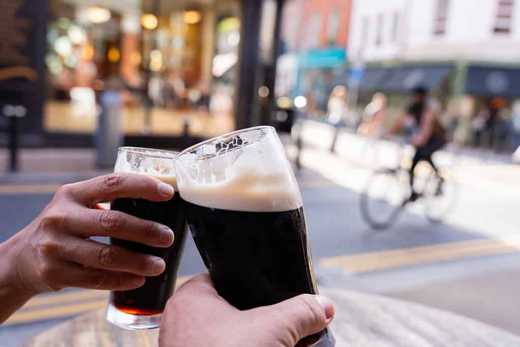 Close-up of two hands toasting each other with Guinness beers on a central Dublin street having a good time on a beautiful autumn morning