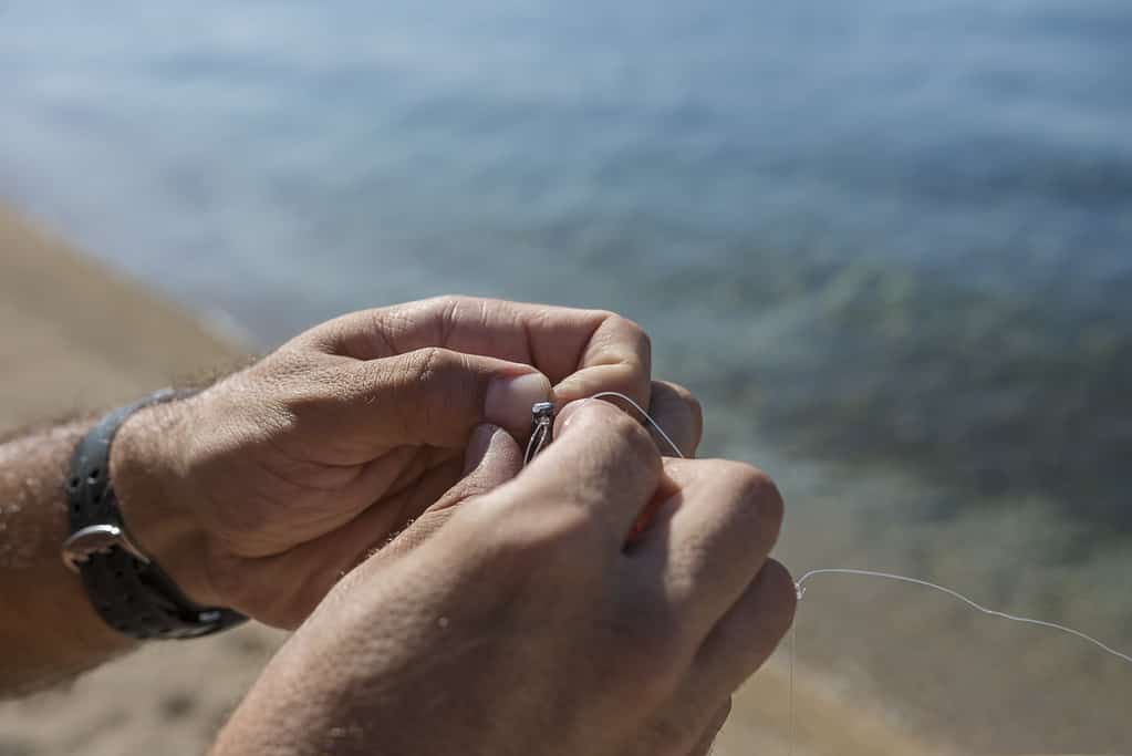 A man knots a fishing hook and lead at the beach