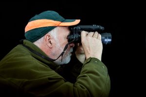 Night hunter. A hunter observes his hunting ground in the darkness with a night vision device.
