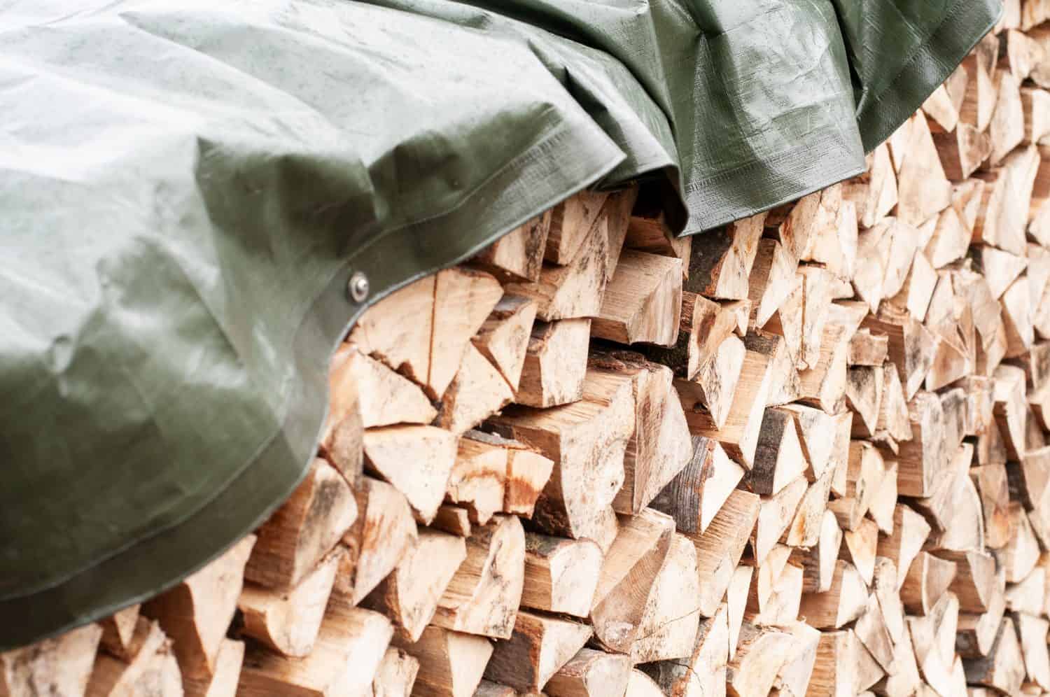 close-up of a stack of chopped firewood covered with a tarpaulin