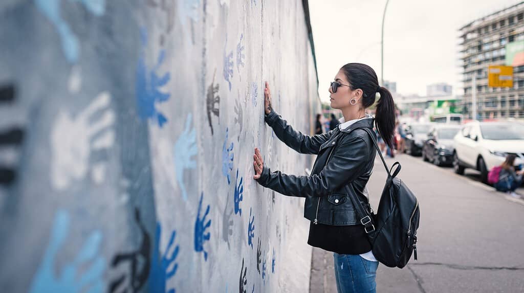 Young woman in front of Berlin Wall.