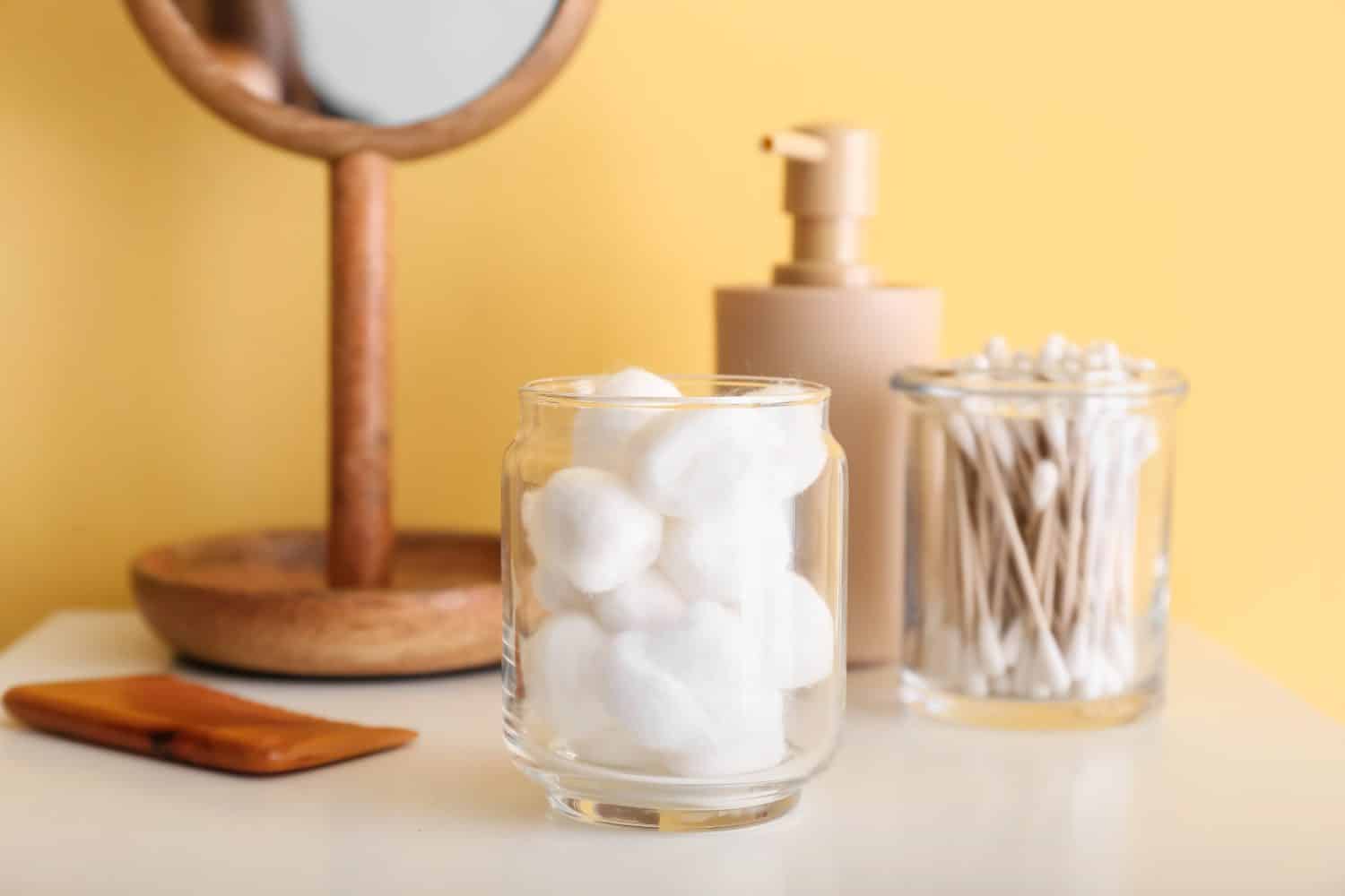 Container with soft cotton wool on table near yellow wall
