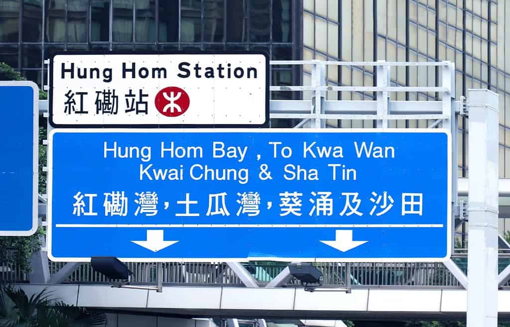 Large road signs in English and Chinese on Hong Kong highway show directions to different parts of the city