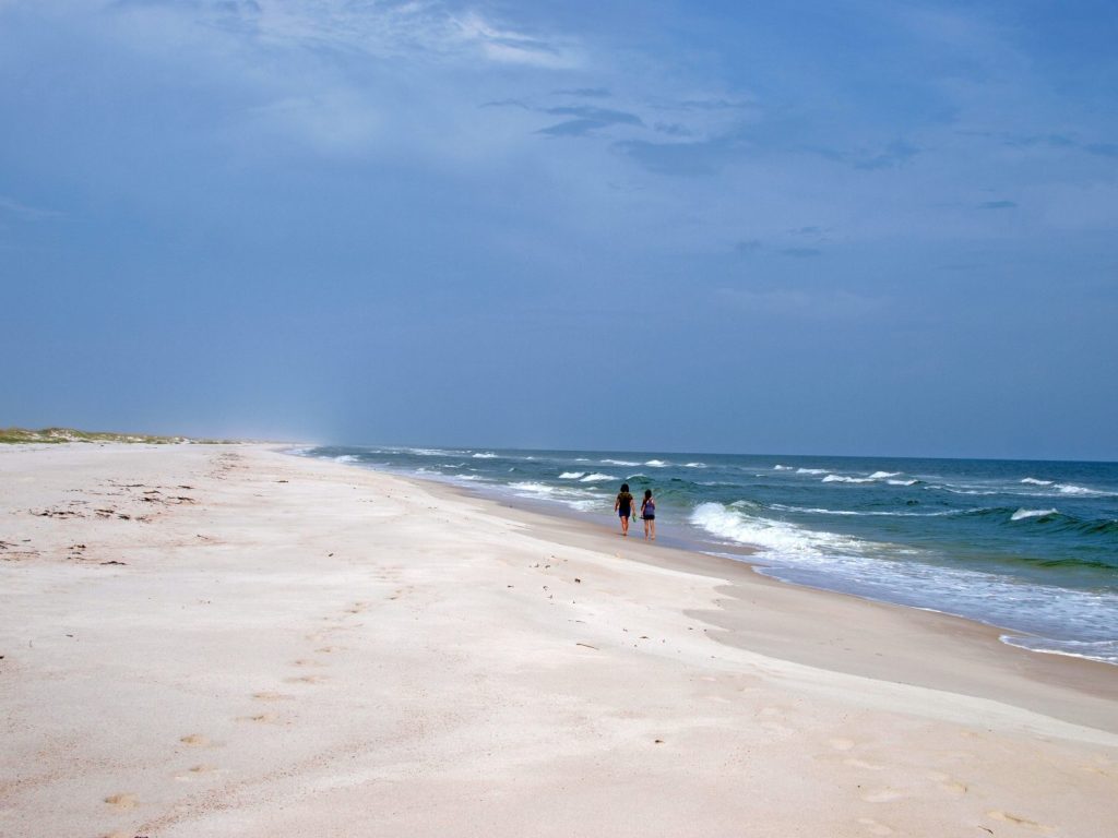 Ladies walking in the deserted beach of St. George Island State Park in the Gulf of Mexico.