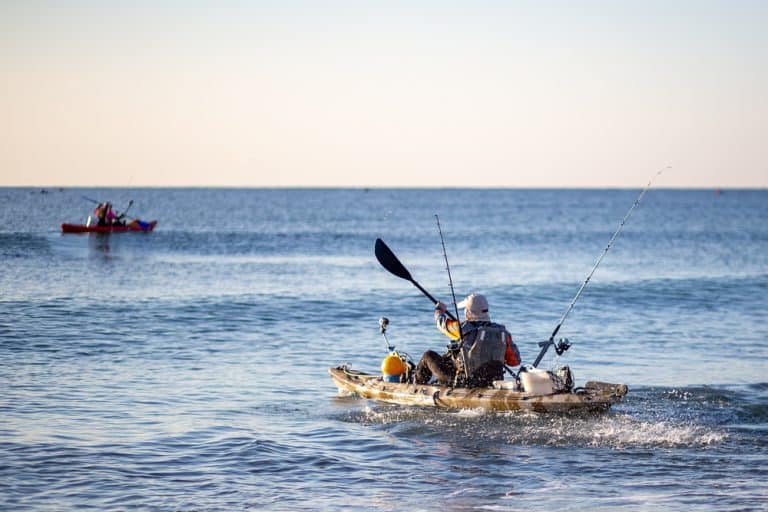 Man fishing in a kayak in the sea. Fisherman kayaking in the Mediterranean sea