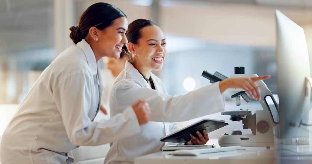 Teamwork, scientist or women celebrate for success, medicine breakthrough or partnership in lab. Science, collaboration or happy doctors celebrate medical support, goal target or DNA news with smile