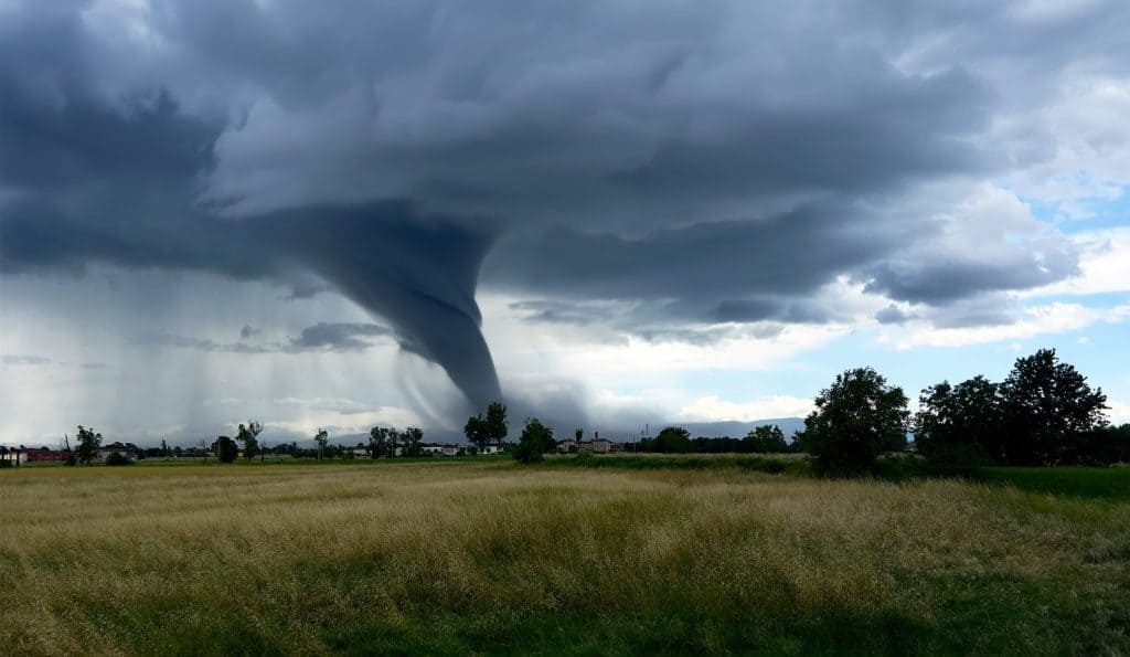 Tornado forming over farmland, dramatic storm clouds touching ground