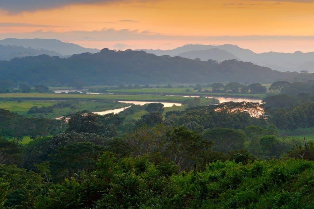 Rio Tarcoles, Carara National Park, Costa Rica. Sunset in beautiful tropical forest landscape. Meanders of river Tarcoles. Hills with orange evening sky. Holiday in Costa Rica.