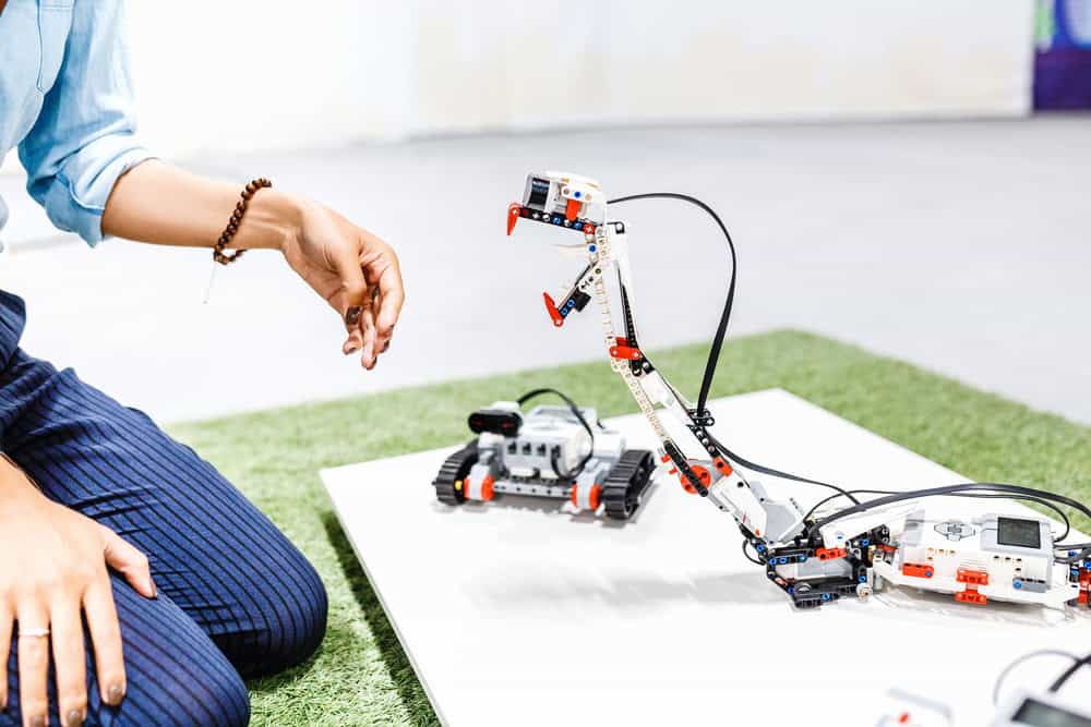 Hand touches a snake robot assembled from a designer, education and School of Robotics concept