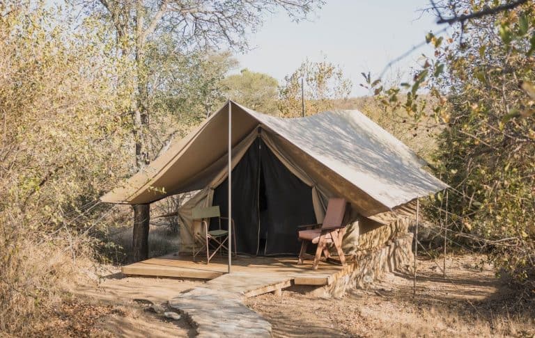 Tent camping, outdoor in the South African bush on a safari camp in the middle of the wilderness. Small glamping tent with wooden platform and directors chair in Bundox Safari Lodge Hoedspruit.