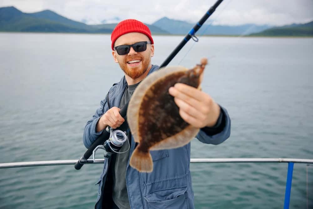 Happy Scandinavian fisherman caught flounder fish with fishing rod, trip north ocean.