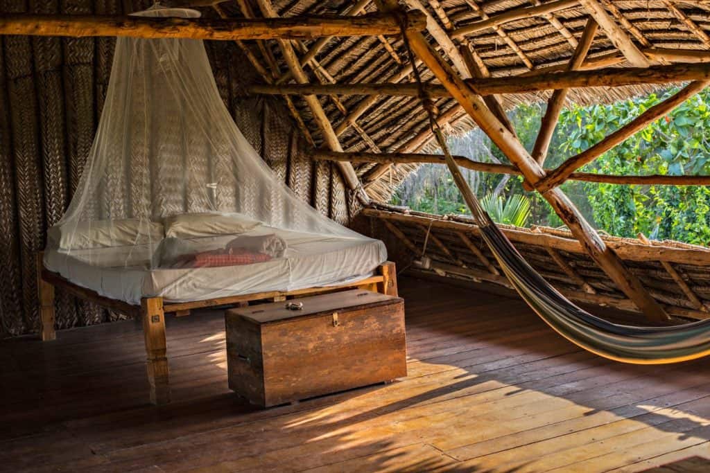 Traditional Zanzibar style open air hostel with wooden furniture, hammock and mosquito net. Cozy wooden interior of Zanzibar hostel.