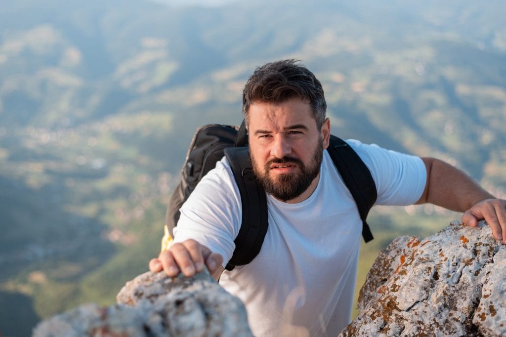 A male climber climbing up on the mountain rock peak cliff extreme sport outdoor adventure travel.