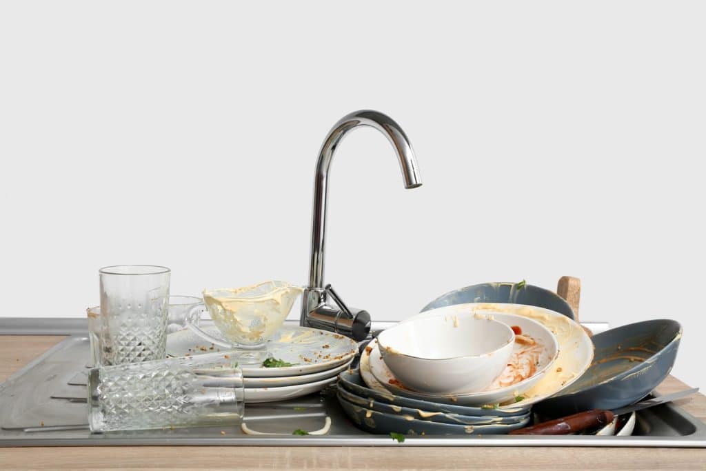Dirty dishes in sink near white wall