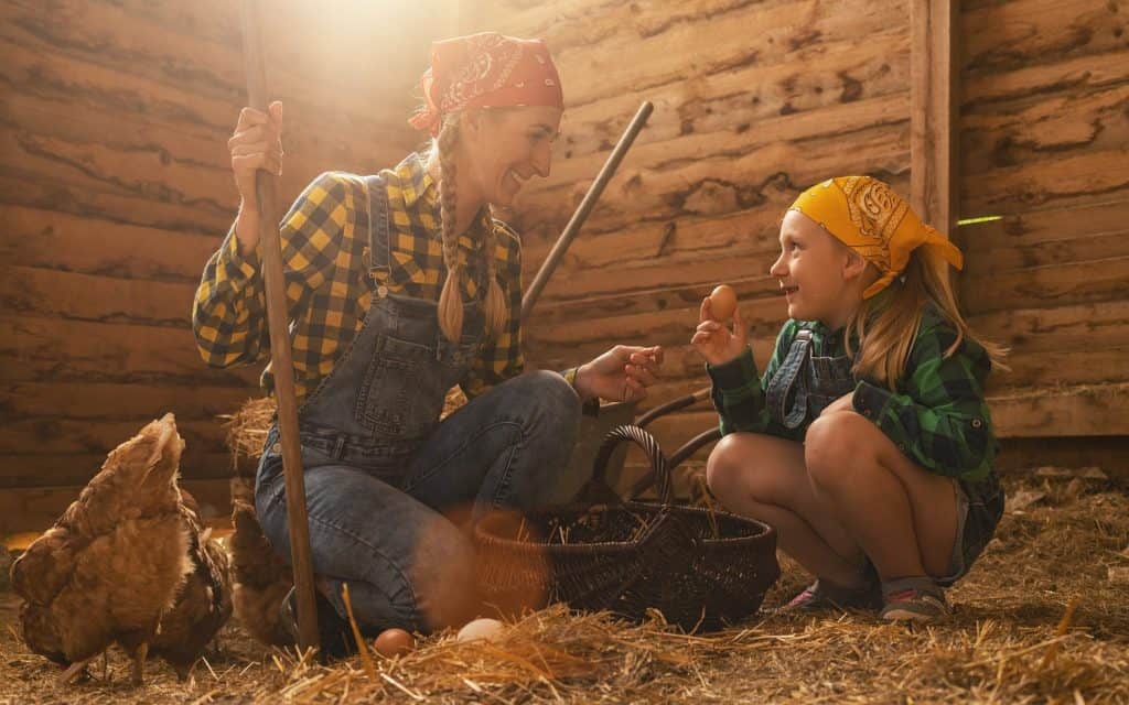 Proud chicken farmer woman and her daughter showing the organic eggs of her hens produced in a henhouse