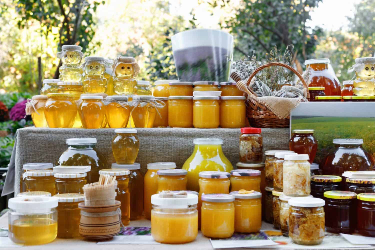 Assortment of honey jars at market stall. Sale of natural honey in fair outdoor. Production of honey.