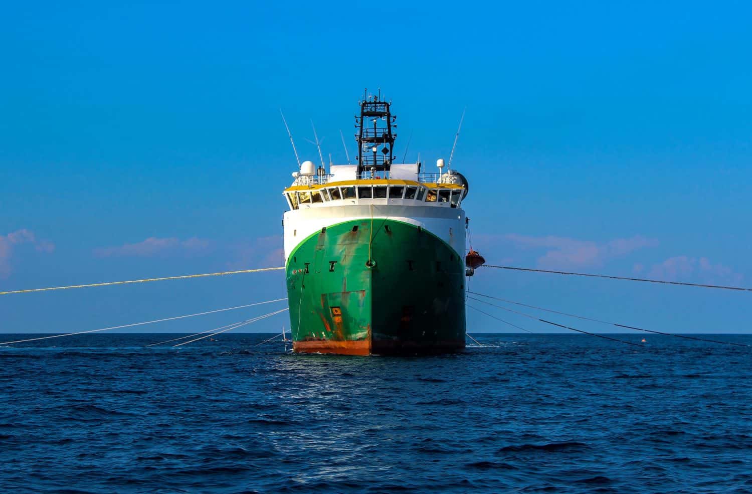 Seismic survey vessel seen from straight ahead with all towed in sea equipment deployed. Oil and gas exploration.