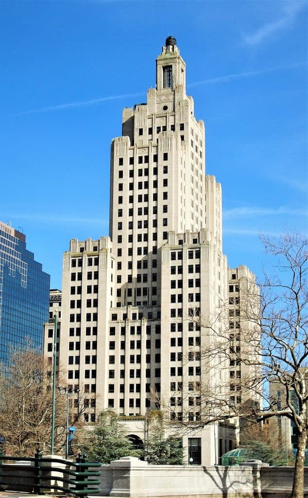 Tall, greyish building with lots of windows against blue sky.
