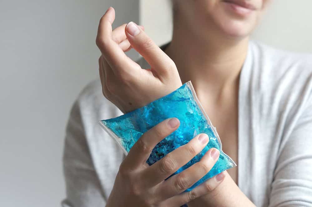 Wrist pain. The woman puts the gel pack to the hand. First aid.                          
