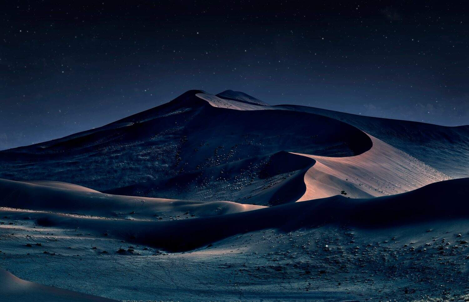 desert of namib at night with orange sand dunes and starry sky.
