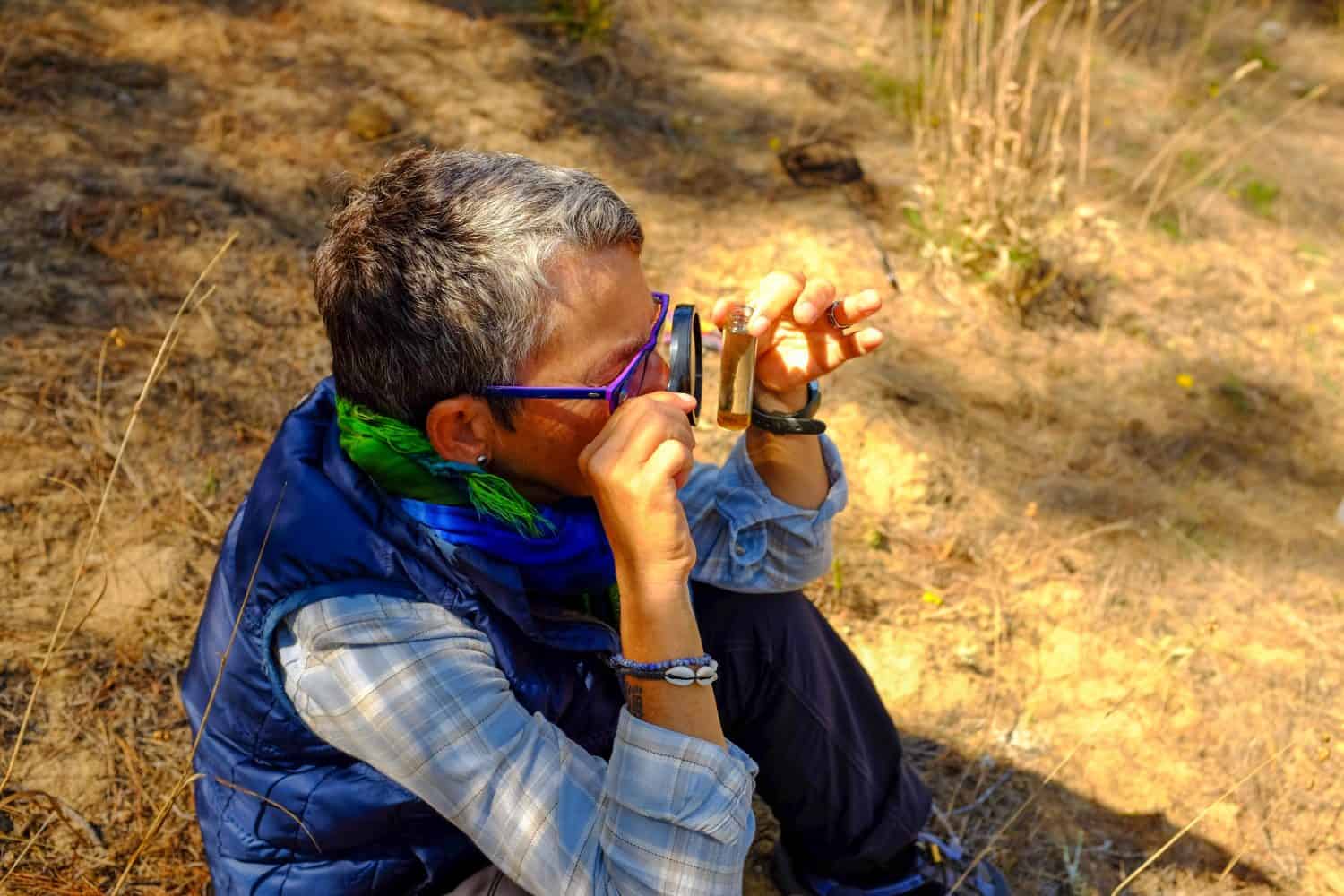 Woman Using Magnifying Glass to Look Into Test Tube