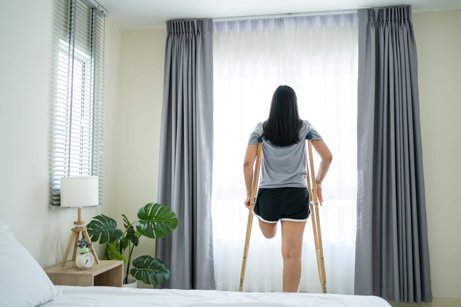 Asian young amputee leg woman wake up and stretching body in morning. Attractive female having no leg feel happy and relax, getting up from sleep on bed in bedroom at home. Leisure lifestyles in house