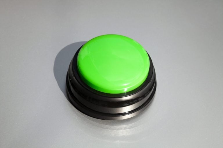 Big green buzzer for answers in a game show isolated on gray. Wireless button for teaching kids or training animals