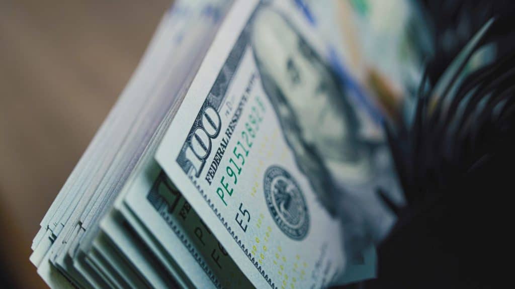 Cash counting machine counts hundred dollar bills. Automatic counting equipment for paper money. Currency counter for exchange. 100 USD banknotes. Finance, investment and banking concept. Close Up.
