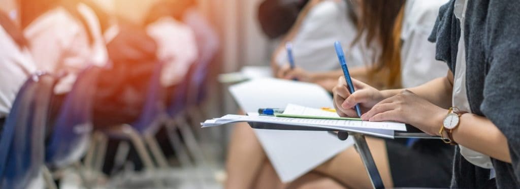 Exam at school with student's taking educational admission test in class, thinking hard, writing answer in university classroom, education and world literacy day concept