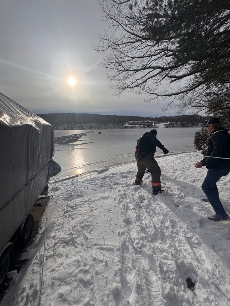 Fire personnel work from the shore and the lake to save the deer