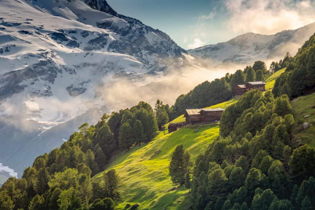 Snowcapped mountains in Stelvio national park with farms, Valfurva, Italian alps