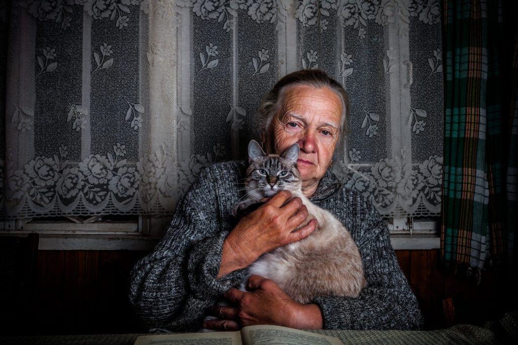 Elderly woman with cat in rustic interior. Toned.