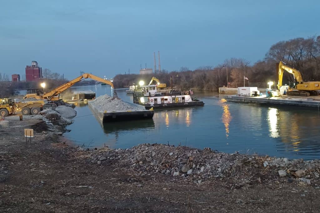 barges in a waterway lifting rocks with cranes