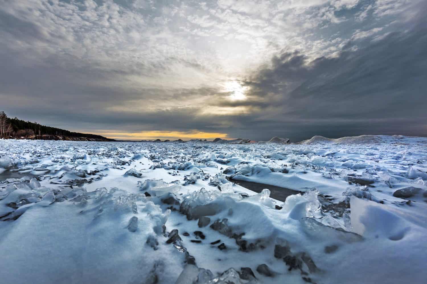 The beginning of the ice age on the Ob River with snow and ice hummocks off the coast. Berdsk, Novosibirsk region, Western Siberia of Russia, November