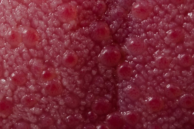 wet-looking red surface with bumps of various sizes