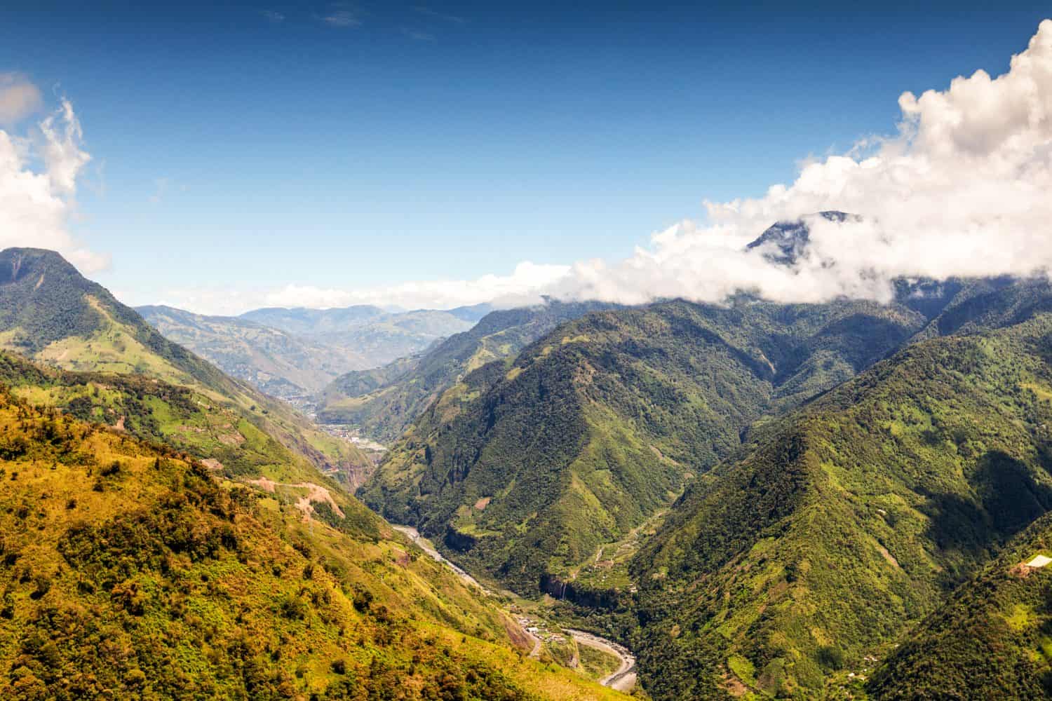 A breathtaking aerial view of Ecuador's Amazon rainforest in Llanganates National Park, showcasing lush green canopy, winding river, and majestic valley.