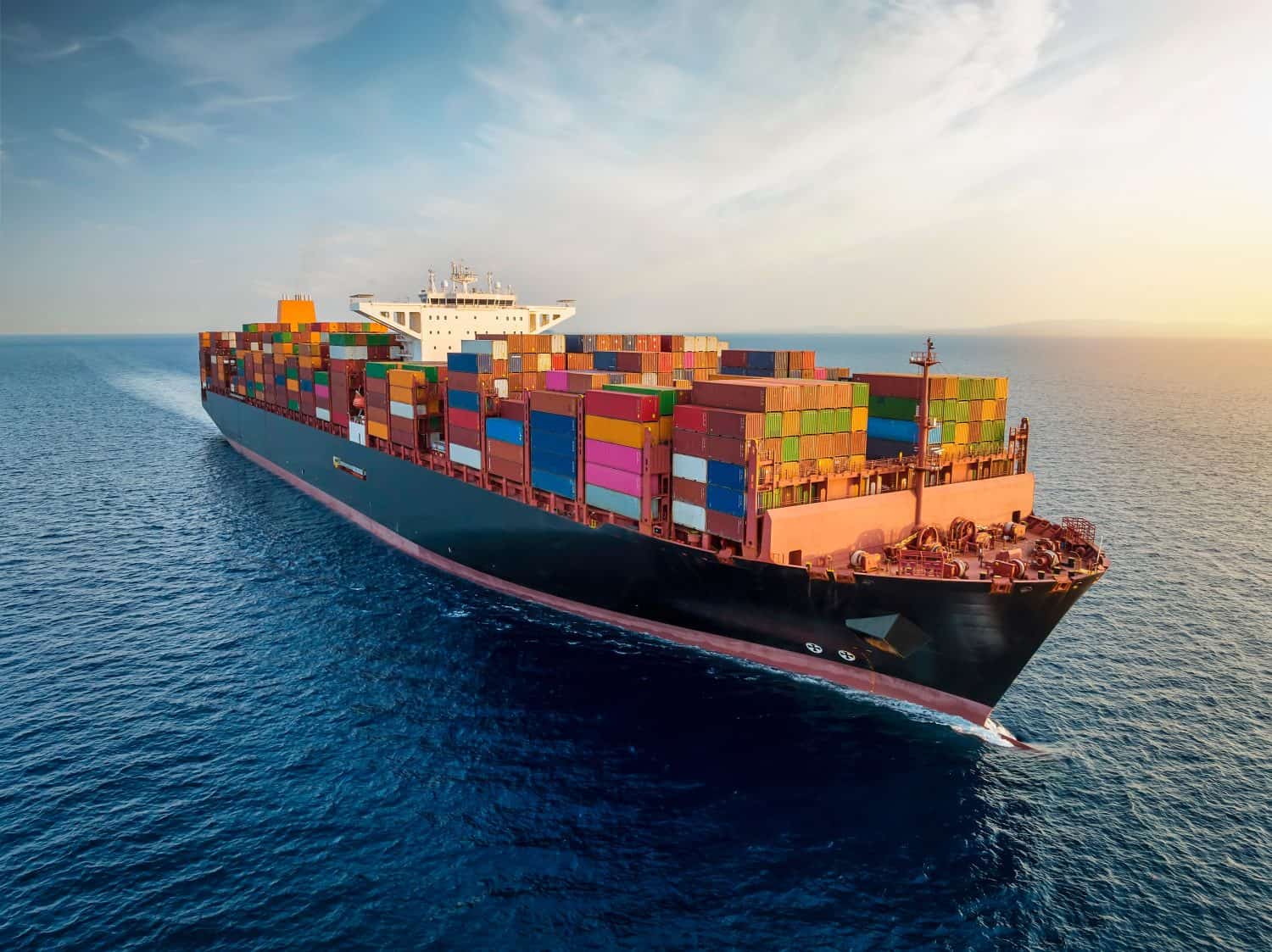 Aerial view of a large, loaded container cargo ship traveling over open ocean