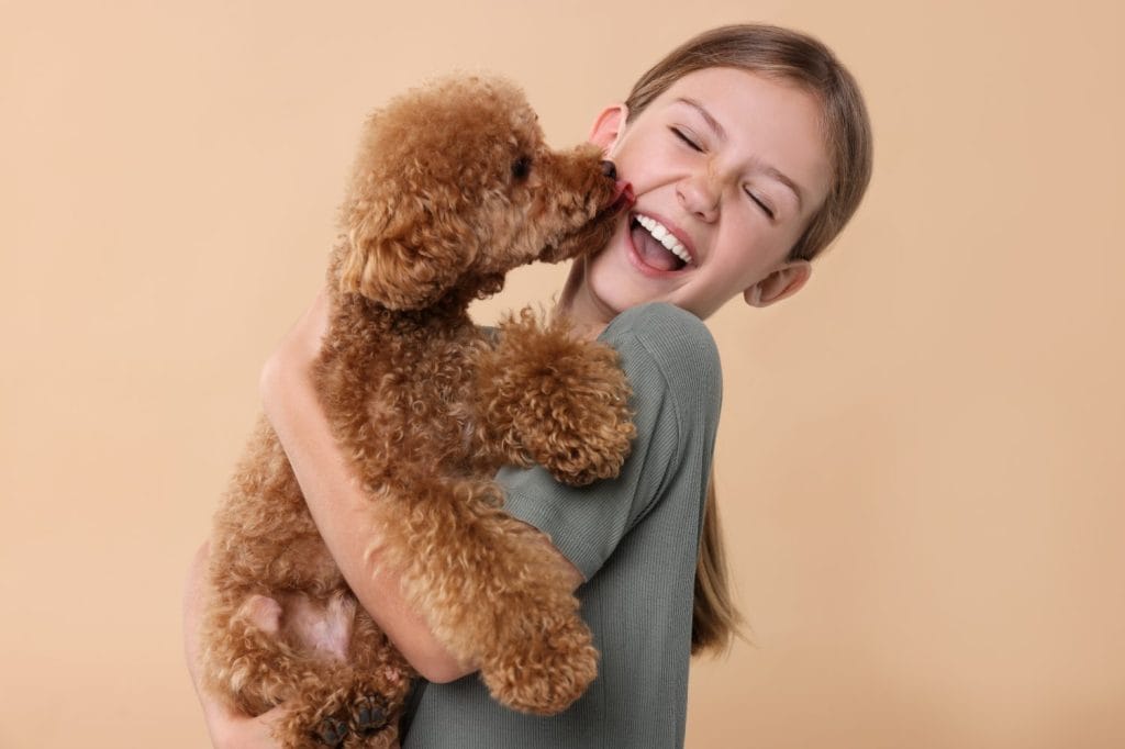 Emotional little child with cute puppy on beige background. Lovely pet