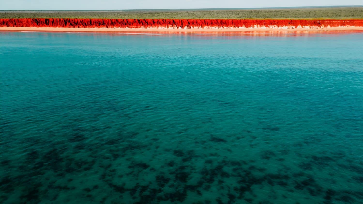 Aerial Photo of turquoise ocean water and red rock cliffs, James Price Point, Kimberley Region, Broome Western Australia