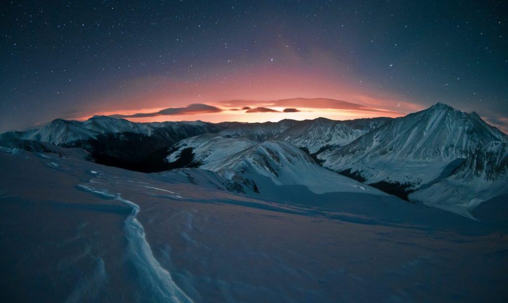Light pollution glows with a certain beauty against the starry night sky. This image was taken after a snowshoe trek above Loveland Pass, west of Denver, Colorado.