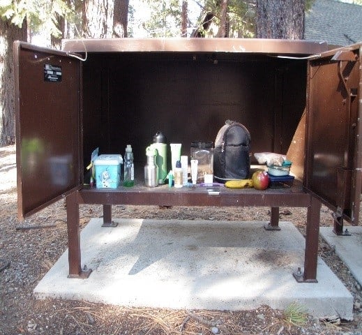 Big metal box on four legs, sitting outside with doors open displaying stuff like food inside it.