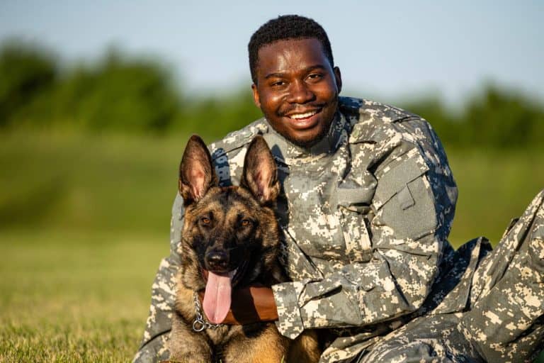 Portrait of soldier in uniform embracing his military dog.