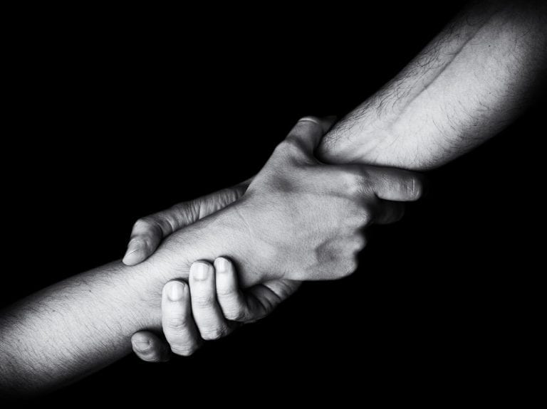 Man saving rescuing and helping woman by holding or griping hand. Male pulling up female. Concept of rescue, love, friendship, support, teamwork, partnership, reaching, pandemic, coronavirus, covid-19