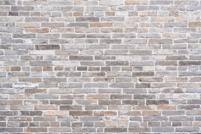 Large weathered, clean, aged, ancient, rustic gray brick wall featuring a mix of grey, tan and white tones in sunlight for vintage exterior, architecture, product background
