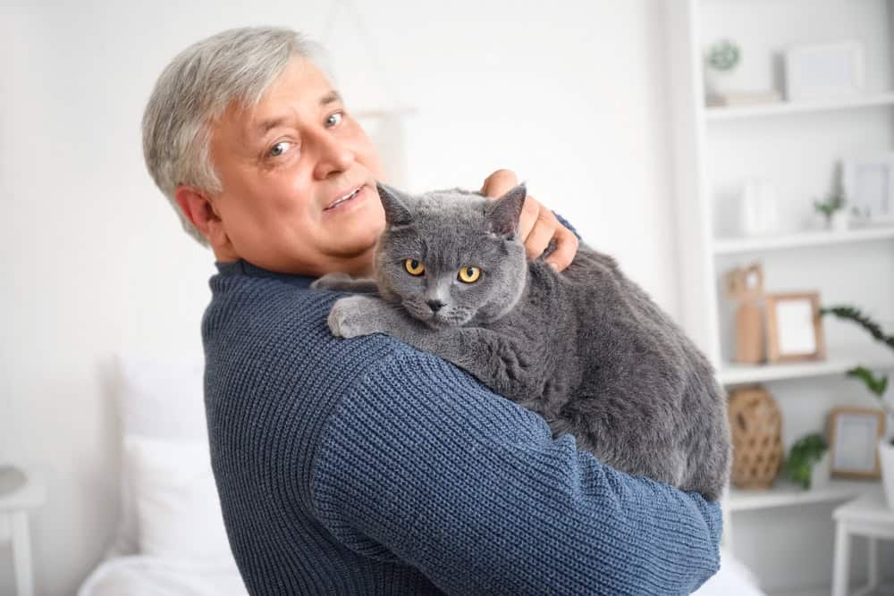 Senior man with cute cat at home