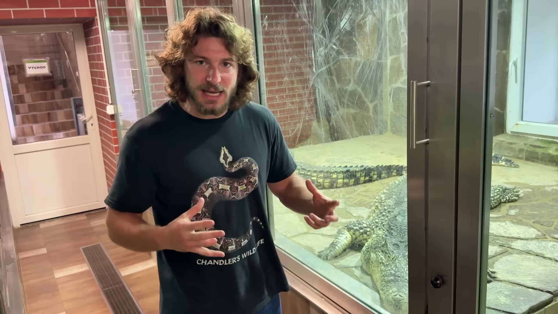 Presenter talking to camera with crocs visible behind