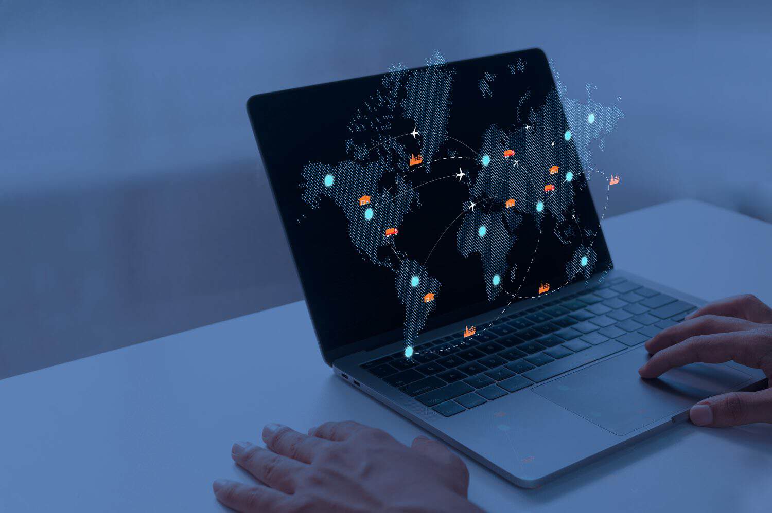 Illuminated laptop displaying a world map with dotted global logistics and transport routes in dark setting